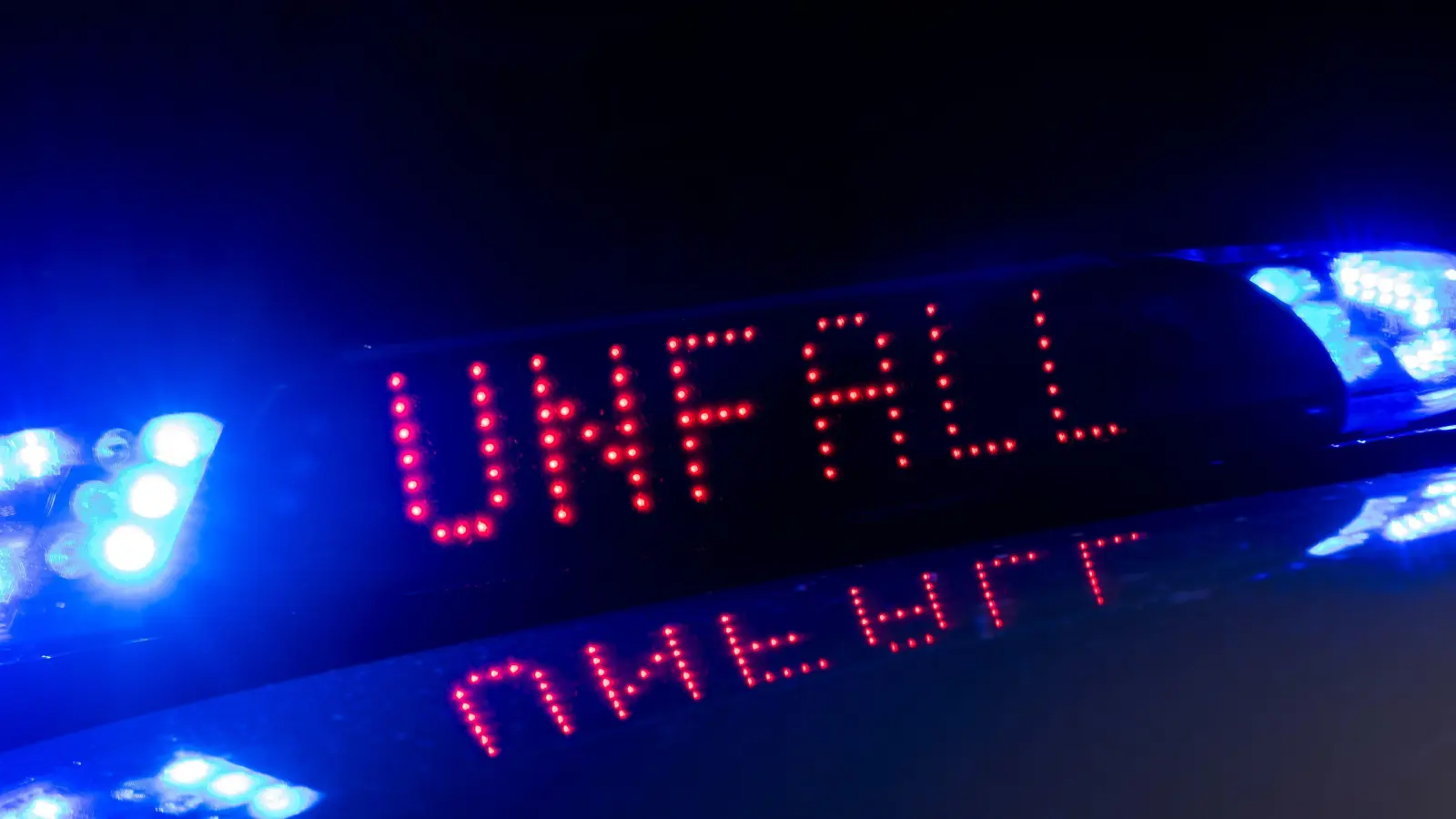 Das Blaulicht auf einem Fahrzeug der Polizei leuchtet in der Dunkelheit, während auf dem Display der Hinweis «Unfall» zu lesen ist. (Archivbild: Monika Skolimowska)