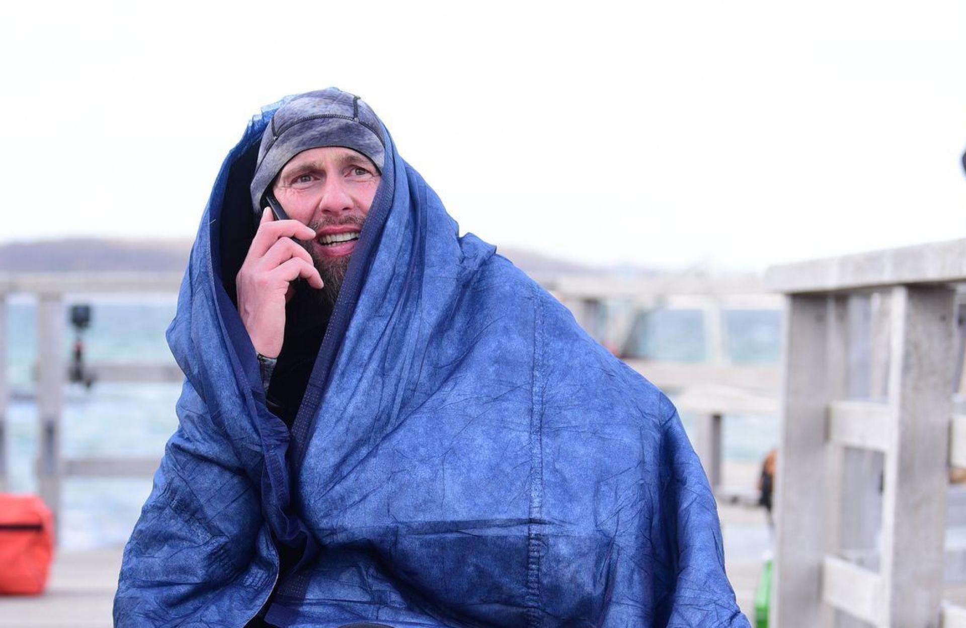 Robert Marc Lehmann geht auf Tuchfühlung mit einem gestrandeten Wal in der Ostsee.  (Bild: Daniel Bockwoldt/dpa)