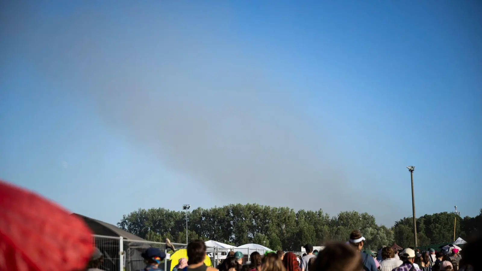 Eine Rauchsäule steigt unweit des Festivalgeländes in die Luft.  (Bild: Philip Dulian/dpa)