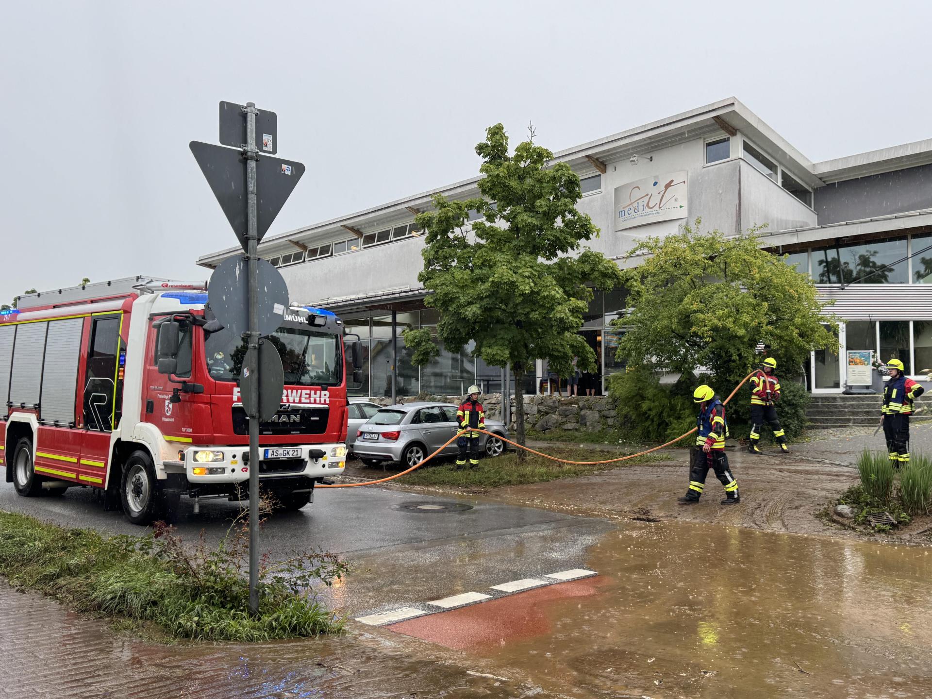 Nachdem ein Radlader den dicksten Dreck weggeschaufelt hatte, säuberte die Feuerwehr mithilfe von Schläuchen die verschlammte Sebastian-Kneipp-Straße beim Medifit in Kümmersbruck. (Bild: Heike Unger)