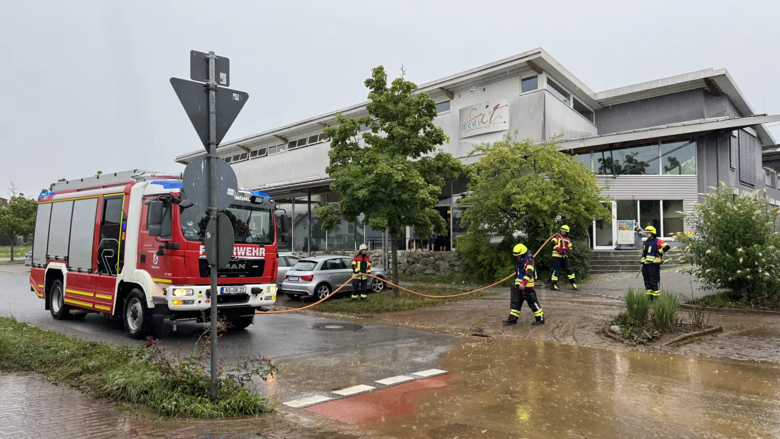 Nachdem ein Radlader den dicksten Dreck weggeschaufelt hatte, säuberte die Feuerwehr mithilfe von Schläuchen die verschlammte Sebastian-Kneipp-Straße beim Medifit in Kümmersbruck. (Bild: Heike Unger)